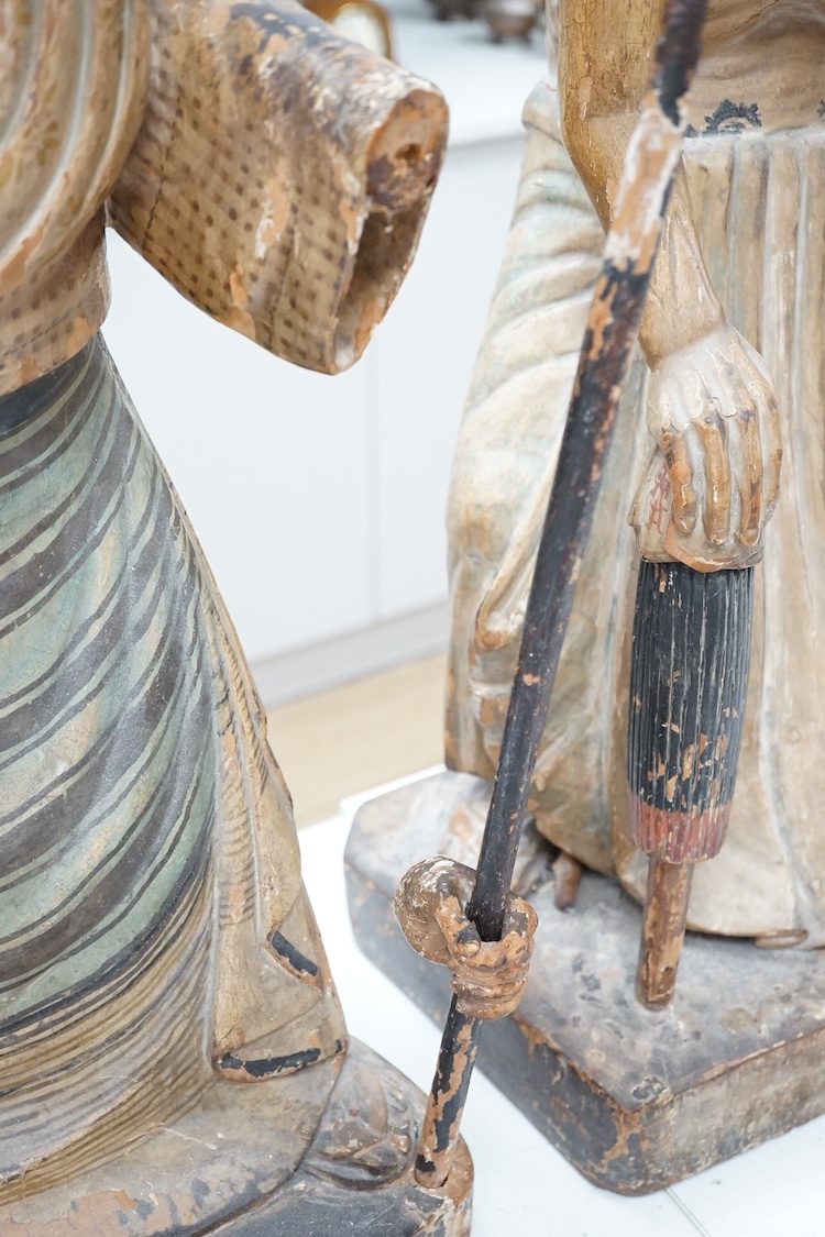 A pair of large Indonesian carved and painted wood figures of an old monk and a lady wearing a sarong, 19th/early 20th century, 70cm. Condition - hand on monk figure broken.